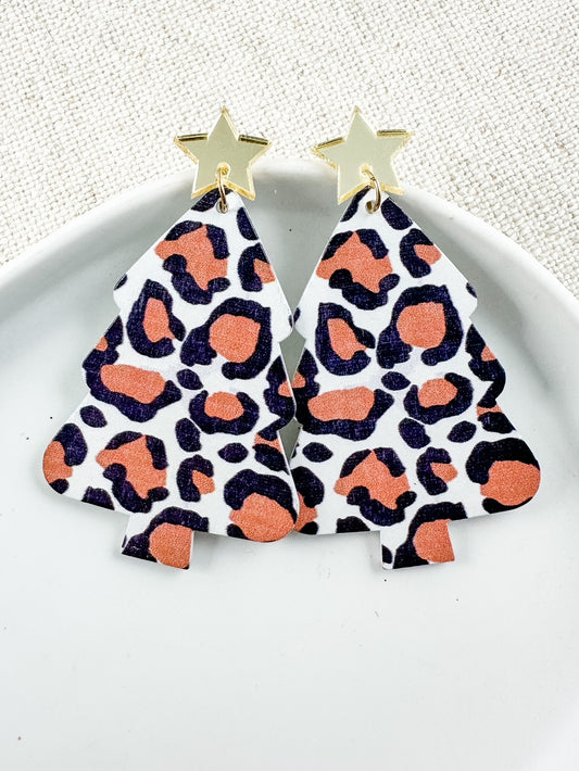 Lightweight wooden Christmas tree earrings with pink leopard print and gold star studs displayed on white dish