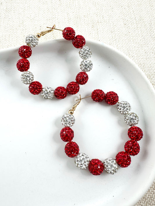 Pair of red and silver sparkle pavé hoops with gold-tone closure shown on white surface