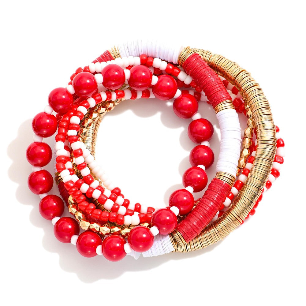 Set of eight red, white, and gold beaded stretch bracelets arranged in a circular stack on a white surface with bright lighting.