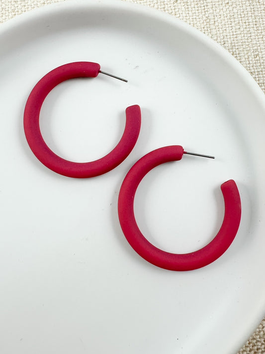 A pair of hot pink colored hoop earrings placed on a white plate.