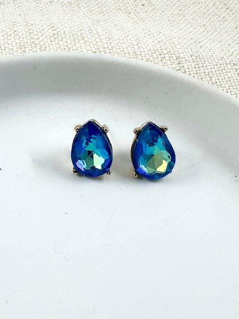 Small blue iridescent teardrop stud earrings on a white plate