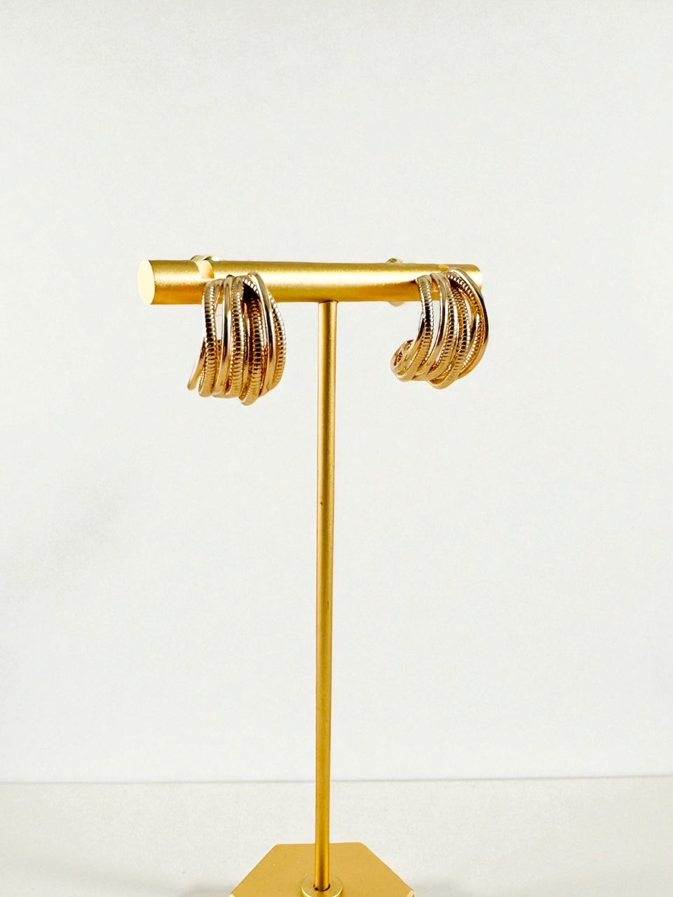 small worn gold multi-band wrap hoops displayed on a gold earring stand