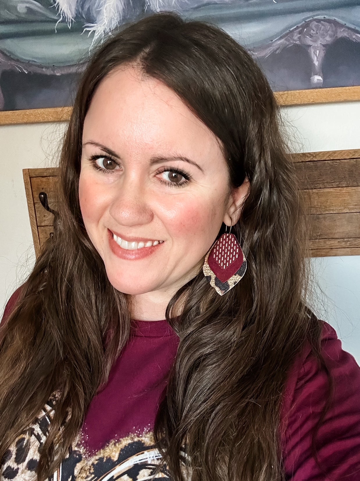 Model wearing large layered maroon suede and leopard leather hoop earrings with antique bronze hoops