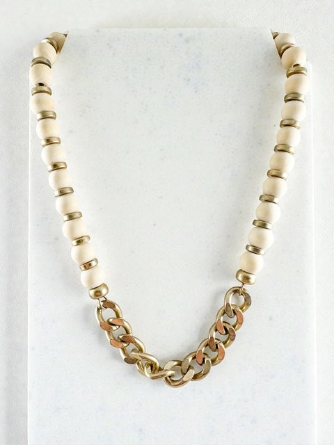 Ivory wood-bead necklace with a gold chain section styled flat on a white surface.