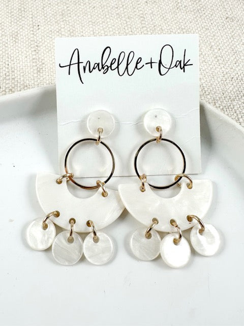 Marbled ivory acrylic drop earrings with gold hoops and round acrylic accents displayed on a white plate