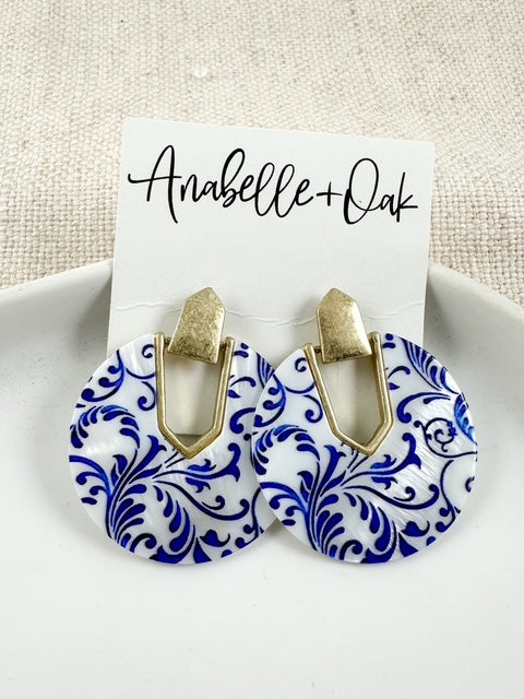 Blue and white acrylic earrings with a swirl pattern and gold geometric links shown on an Anabelle+Oak card.