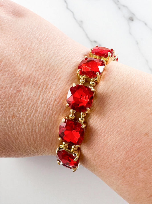 red cushion-cut gemstone bracelet with gold setting shown on a wrist