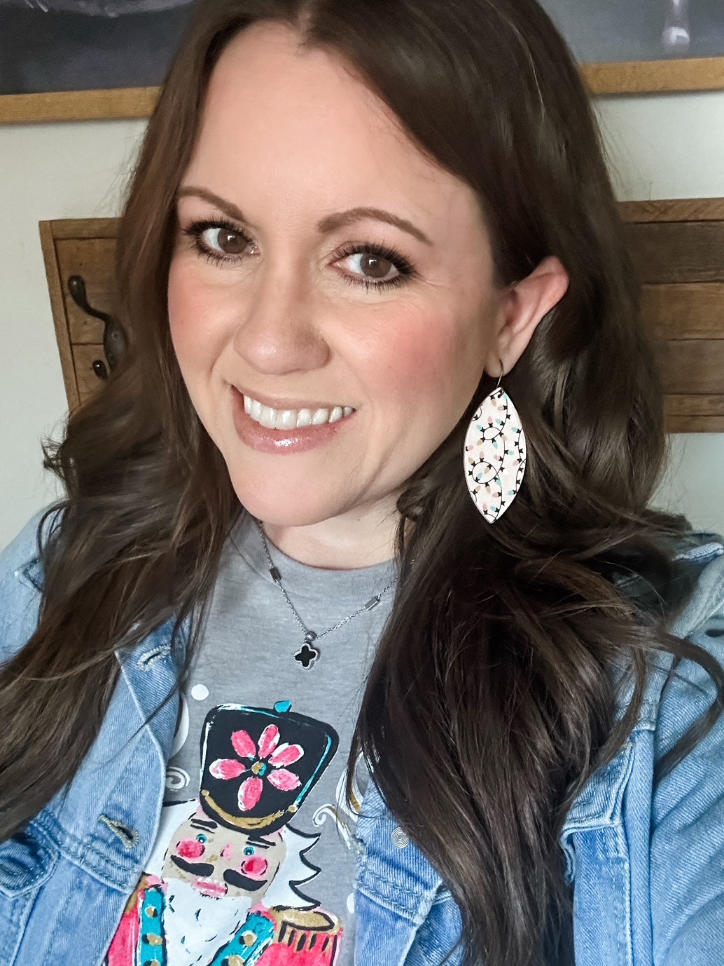 Woman wearing large leaf shape earrings made from blush cork with pastel Christmas lights pattern