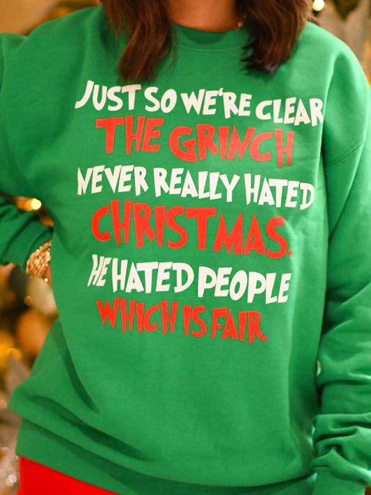 Green sweatshirt with bold red and white holiday text that reads “Just so we're clear the Grinch never really hated Christmas. He hated people which is fair.”
