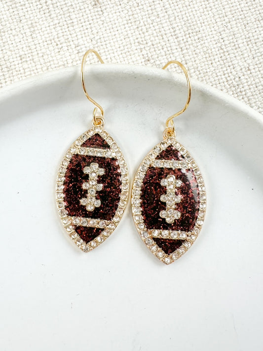 Gold football-shaped earrings with brown glitter and rhinestone details