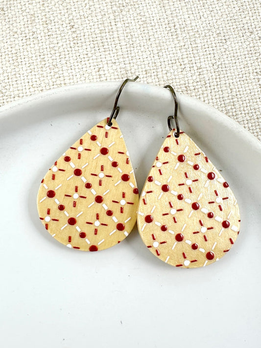 lightweight wood teardrop earrings with red and white stitched pattern shown on a white dish