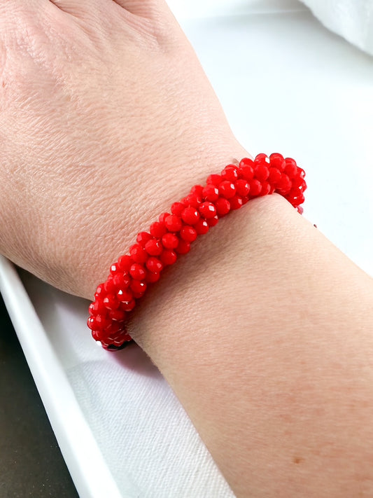 Bracelet made of bright red faceted beads in a full clustered stretch design, shown on a wrist.