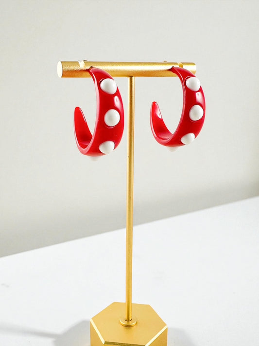 Red and white dot hoop earrings displayed on gold jewelry stand with bright finish