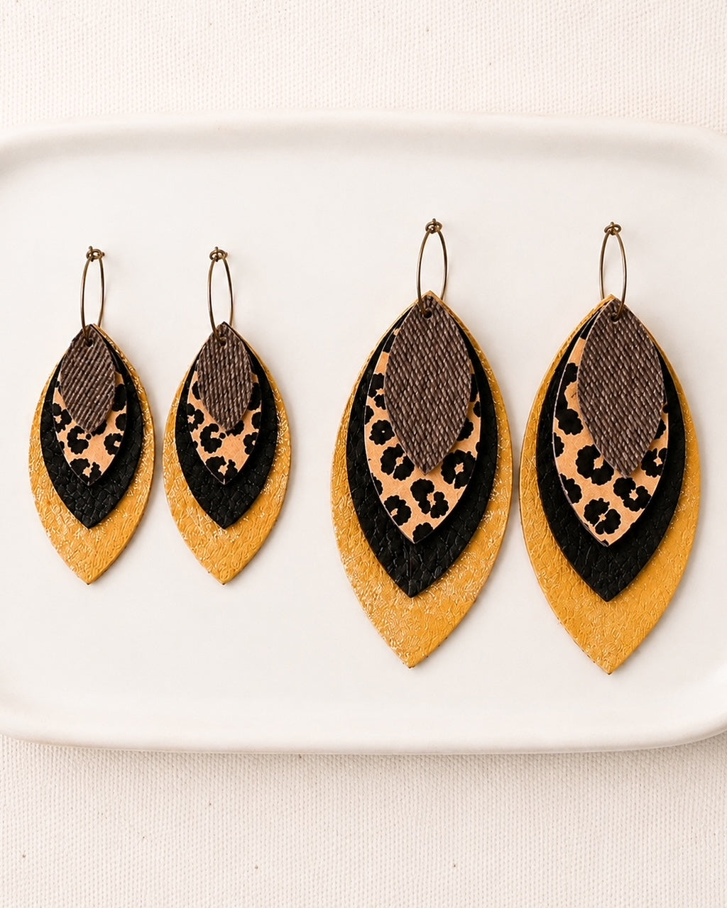 Small and large layered leopard, black and metallic gold earrings displayed side by side for size comparison.