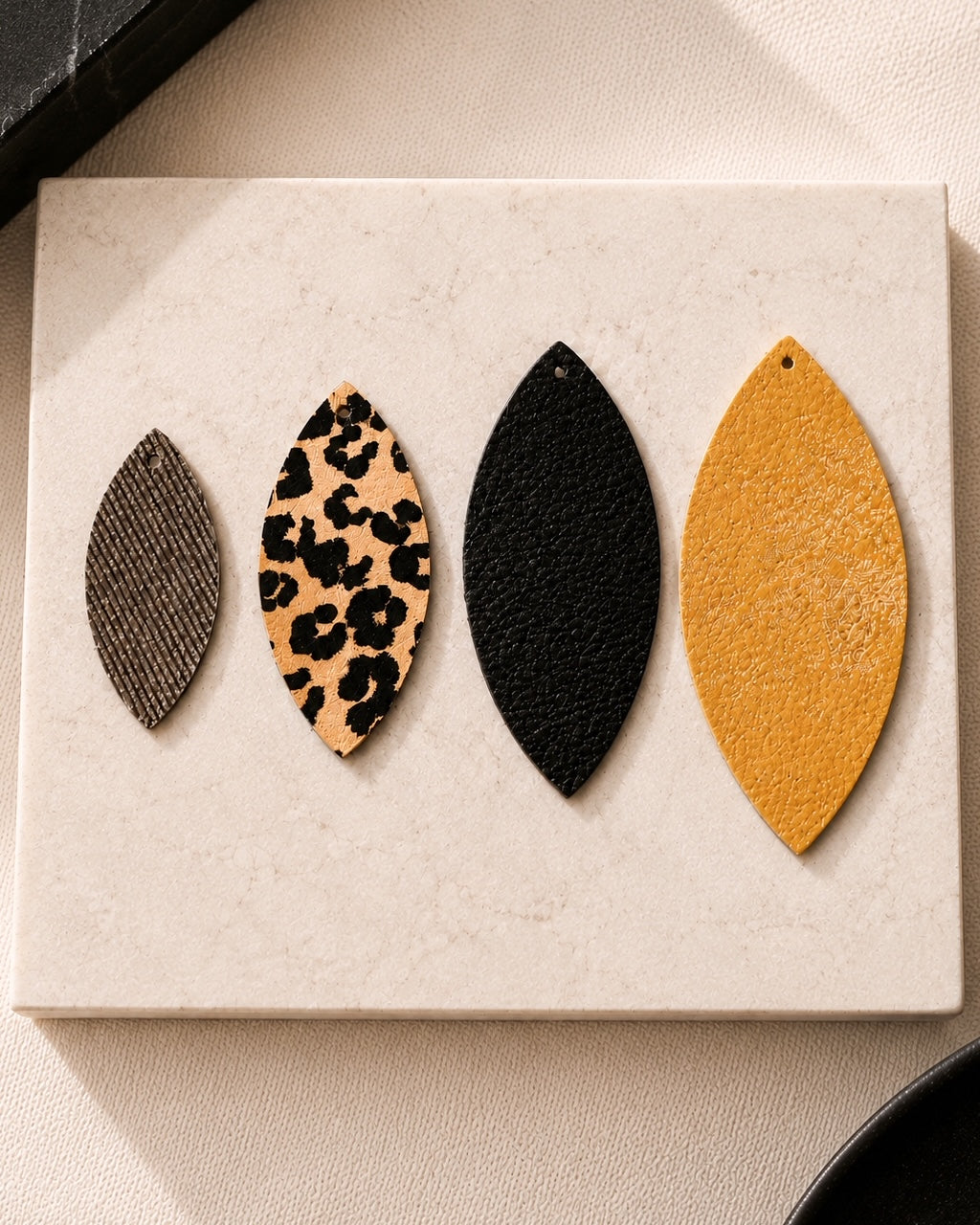 Four removable earring layers displayed separately: textured brown, leopard print, black leather and metallic gold.