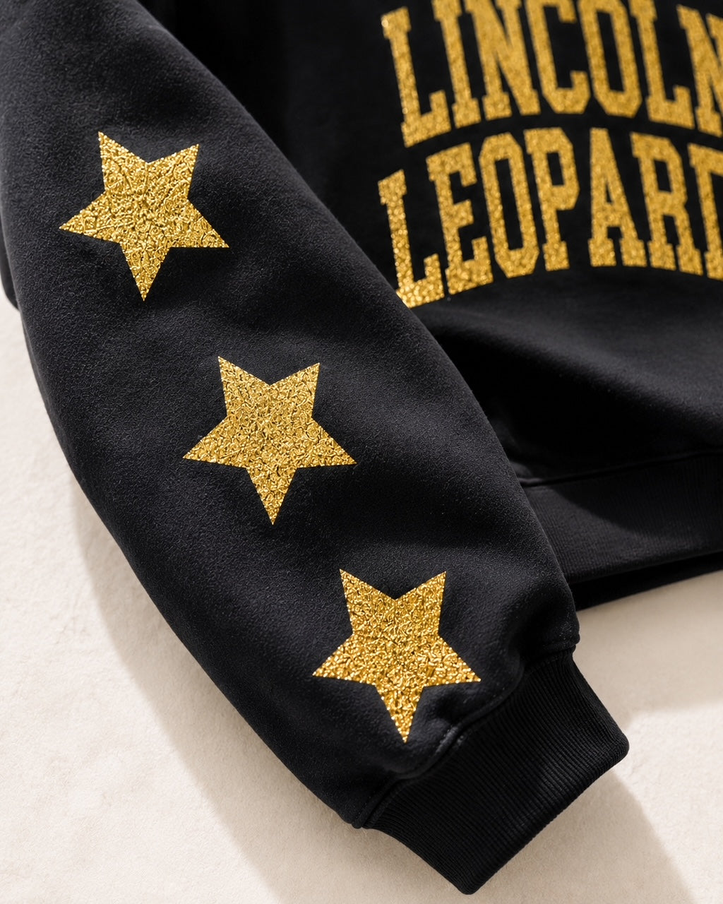 Close-up of gold-glitter stars down the sleeve of the black All-Star Leopard Sweatshirt
