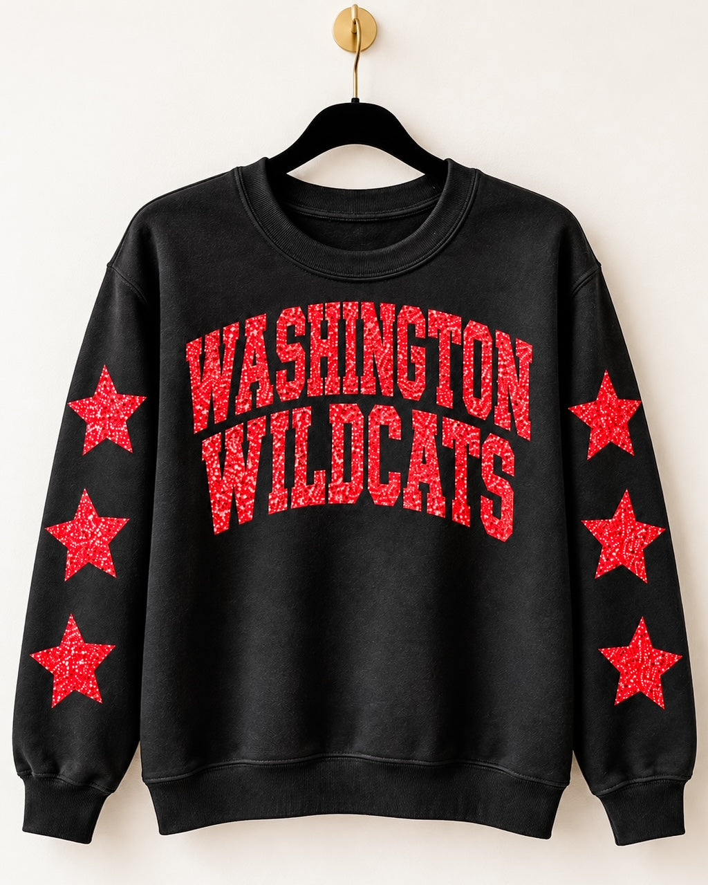 Black Washington Wildcats crewneck sweatshirt with red glitter lettering and three glitter stars on each sleeve, displayed on a hanger.