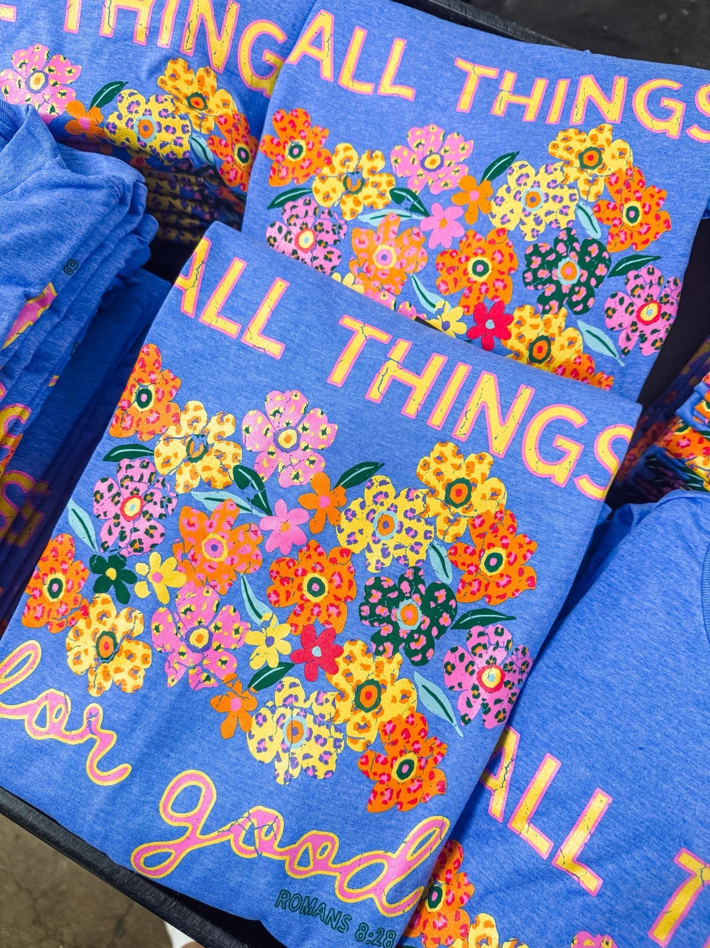 Stack of colorful All Things for Good Romans 8:28 graphic tees