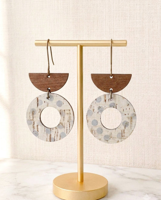 Aspen Mist lightweight geometric cork and walnut wood earrings displayed on a matte gold stand.