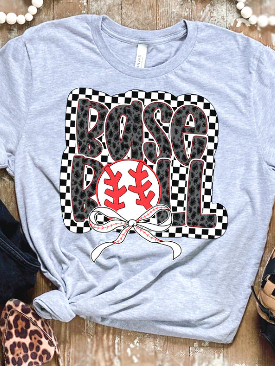 Heather gray baseball graphic shirt laid flat on wooden surface styled with leopard shoes and bracelet.