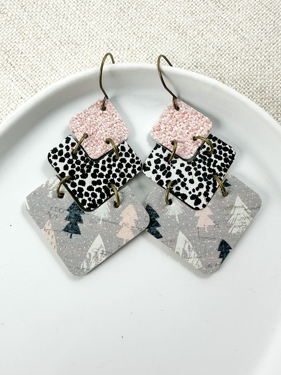 Blush Frost handmade leather earrings displayed in a white jewelry dish