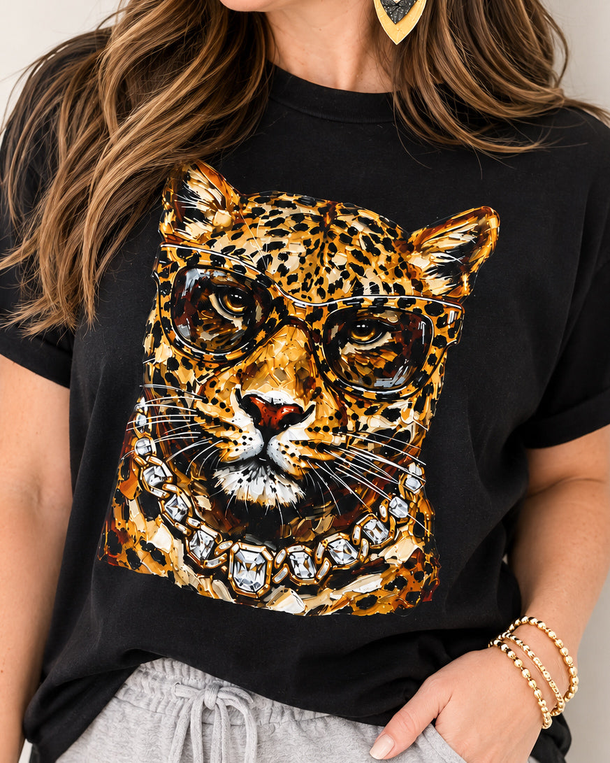 Woman wearing the black Bougie Leopard tee with gray joggers, statement earrings, and gold bracelets