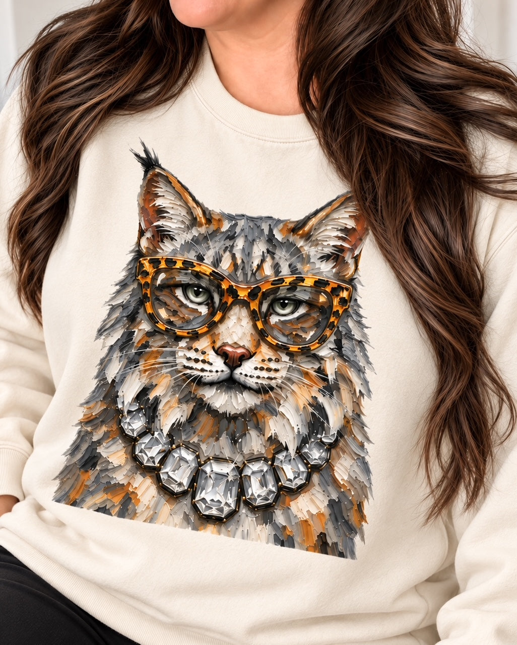 Woman with long brunette hair modeling the cream Bougie Wildcat sweatshirt with oversized glasses and jeweled wildcat graphic.