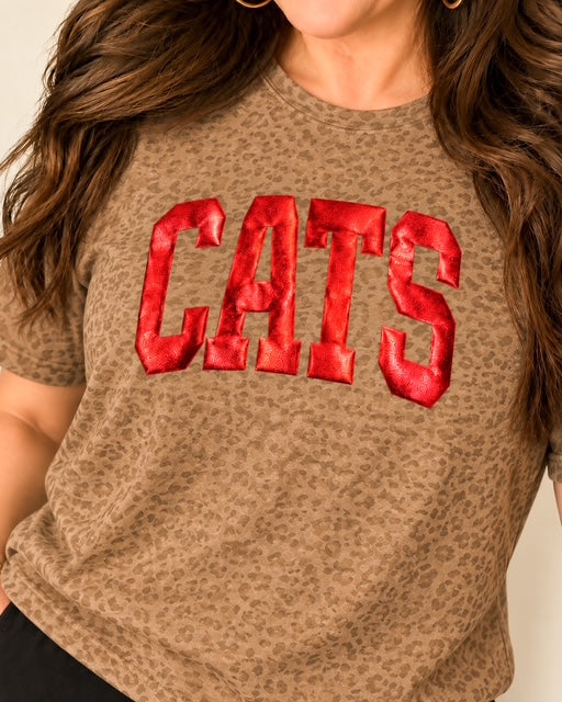 Woman modeling the Cats in the Wild Tee with metallic red puff CATS lettering and gold hoop earrings.