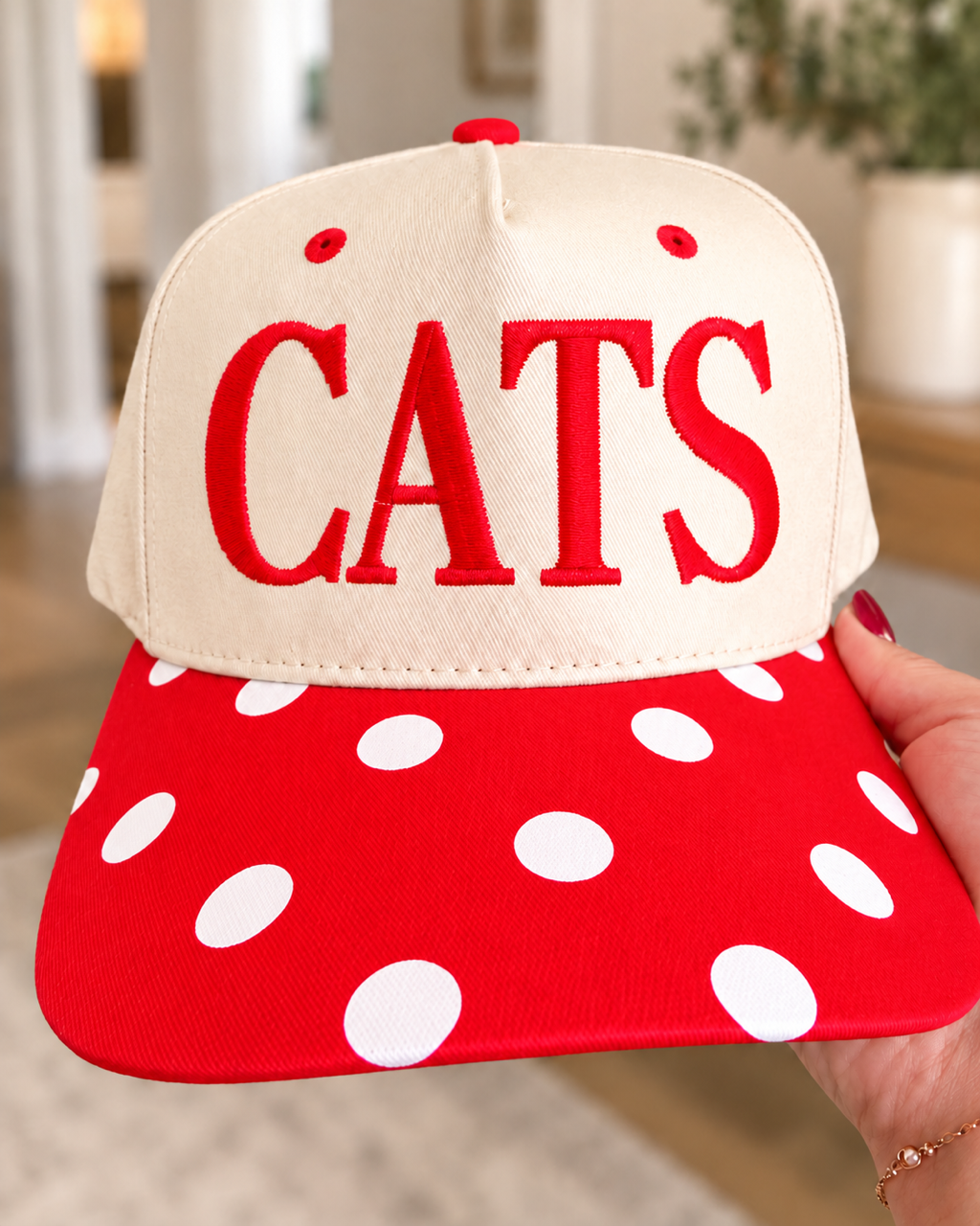 CATS Pep Rally Hat held from the front with oversized red embroidery and a red-and-white polka-dot bill.