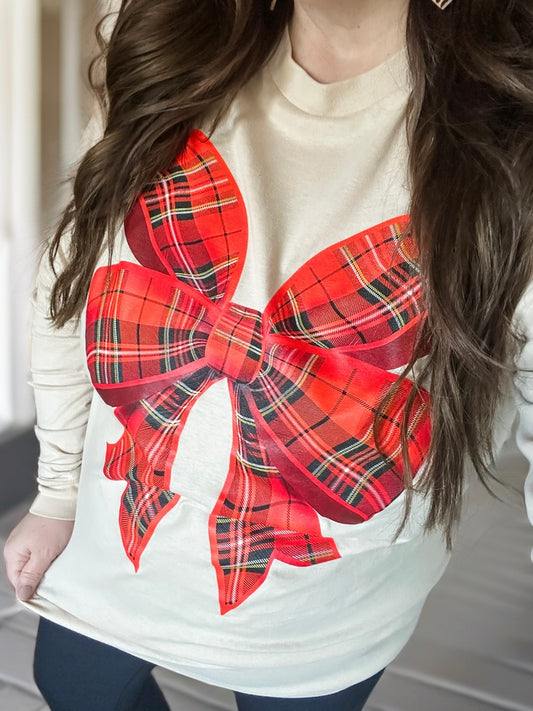 woman wearing cream long sleeve tee with red plaid bow on front