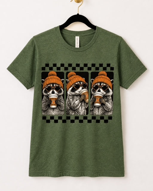 Heather Forest Bella+Canvas Cozy Little Bandits tee with three raccoons in orange beanies holding coffee.