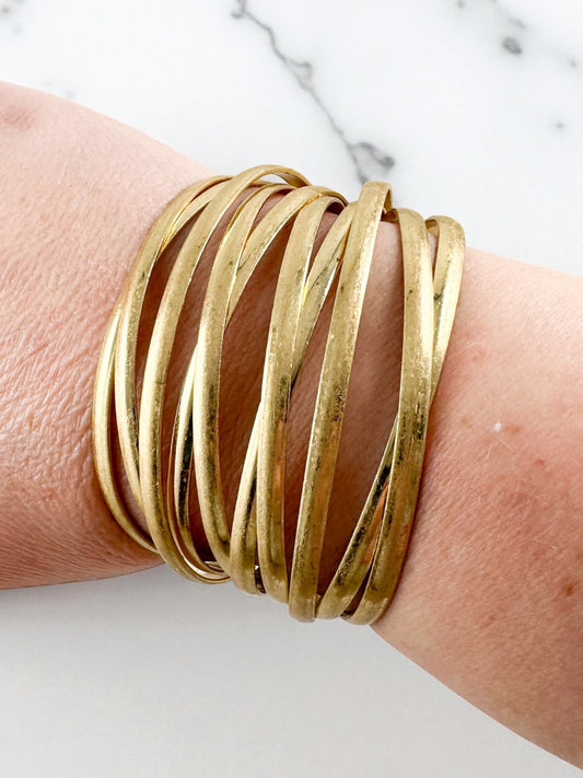 worn gold wrap style cuff bracelet with overlapping metal bands shown on wrist