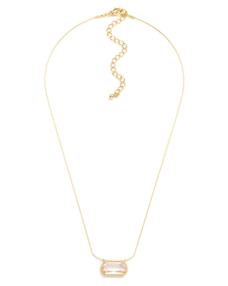 Crystal Clear Necklace featuring a clear faceted rectangular bead in a decorative gold-tone setting on a delicate chain, styled on neutral stone.