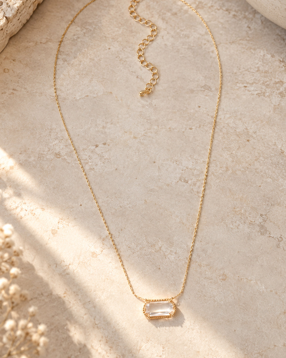 Crystal Clear Necklace with a clear faceted pendant, delicate gold-tone chain, lobster clasp, and adjustable extender on a white background.