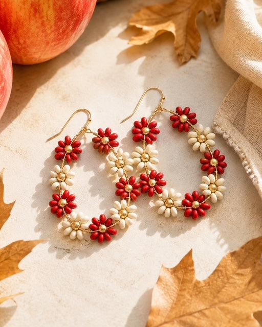 Red and ivory floral earrings styled with apples and autumn leaves for fall.