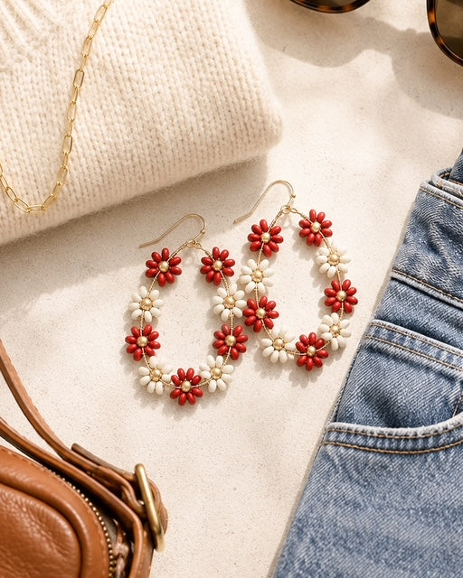Daisy Lane red floral earrings styled with a cream sweater, denim jeans, gold necklace, and handbag.