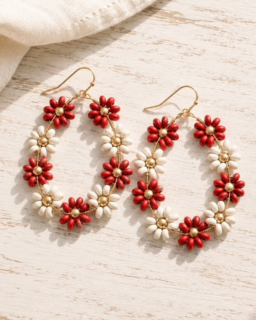Red and ivory floral hoop earrings displayed on a whitewashed wood surface.