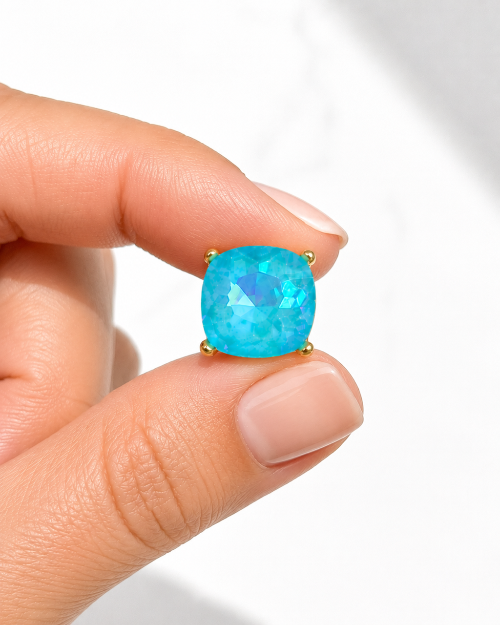 Hand holding turquoise 5/8-inch square stud earrings to show size and scale.