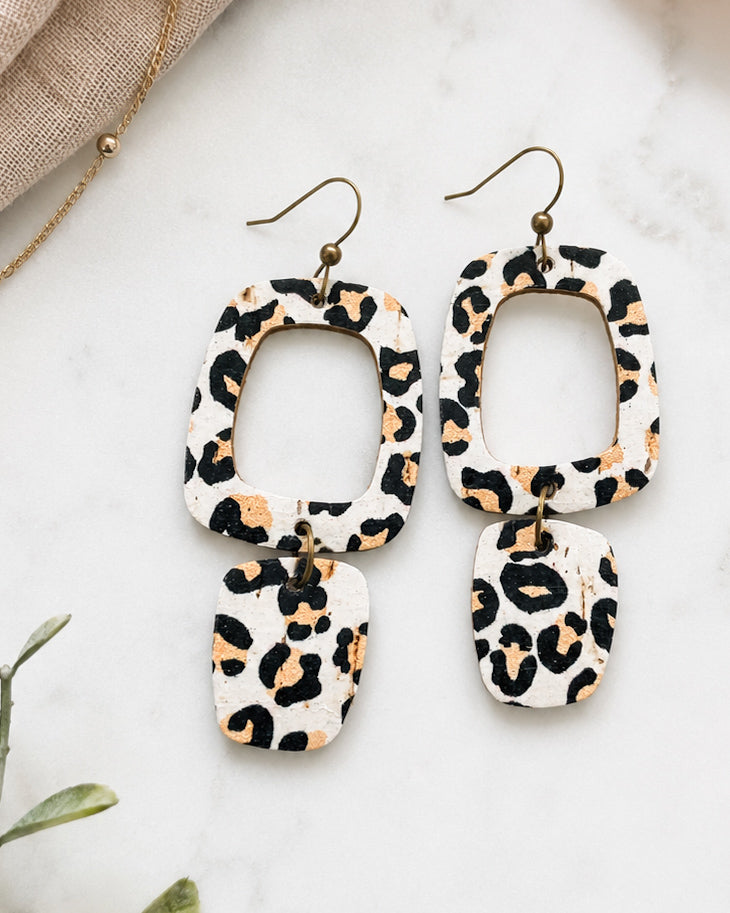 Handmade white leopard cork earrings with genuine leather backing displayed on white marble.