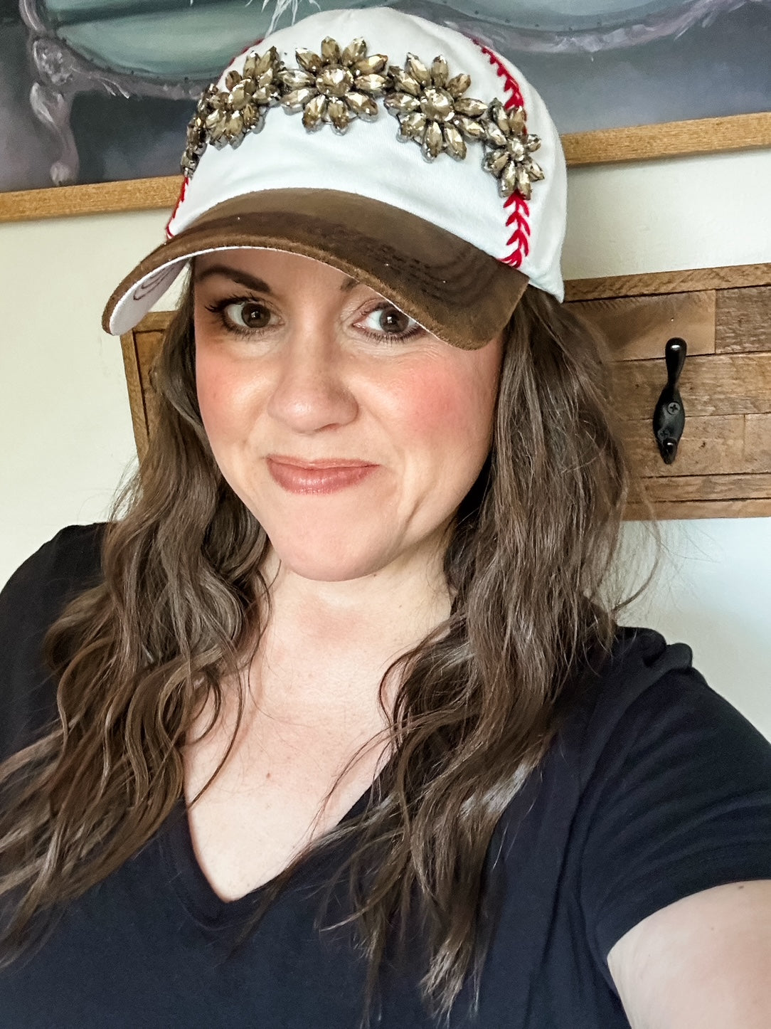 Woman wearing white baseball cap with red embroidered stitching, distressed brown bill, and topaz stone embellishment.