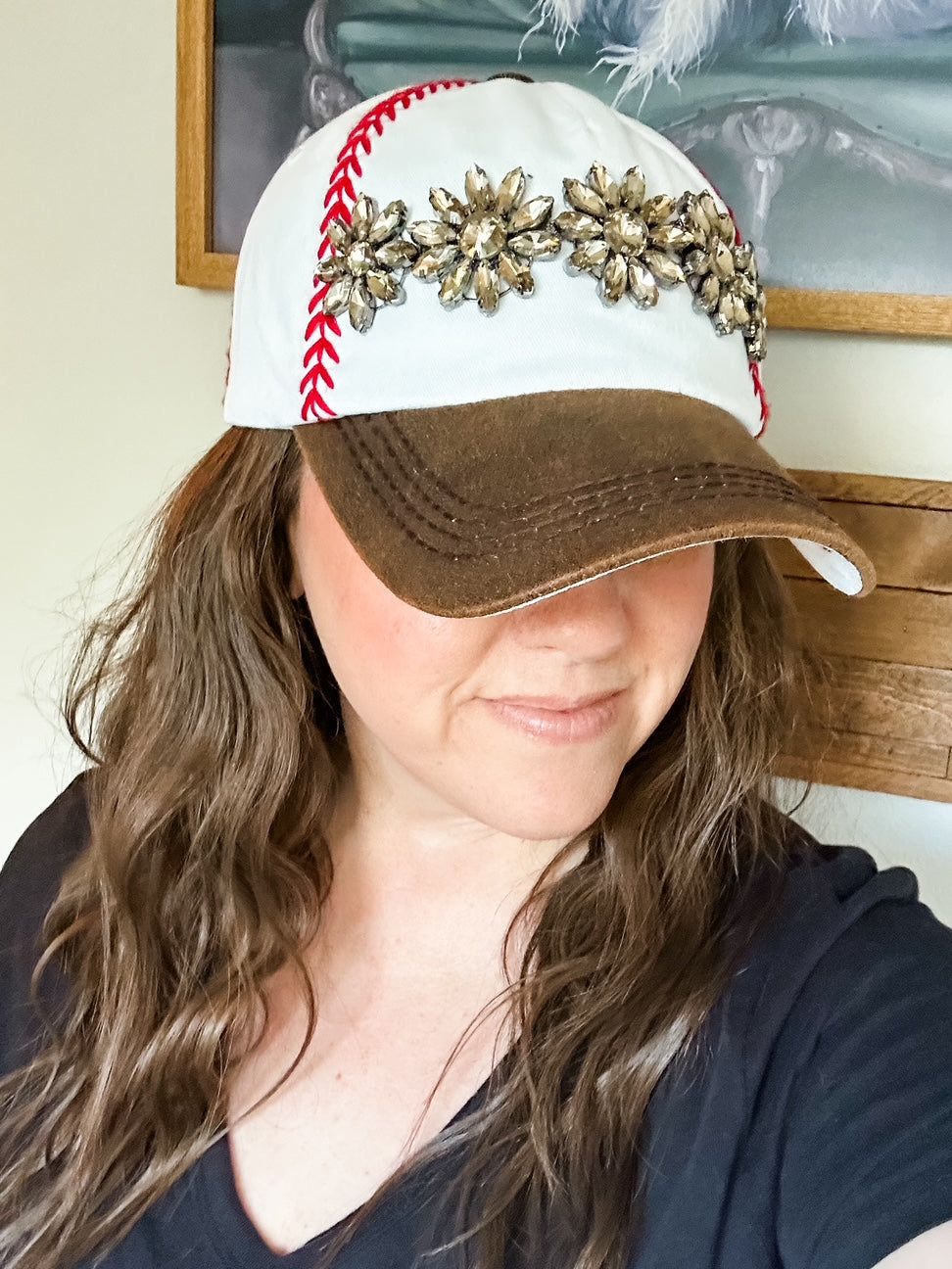 White baseball cap with red embroidered stitching, distressed brown bill with worn leather look, and topaz stone accents.