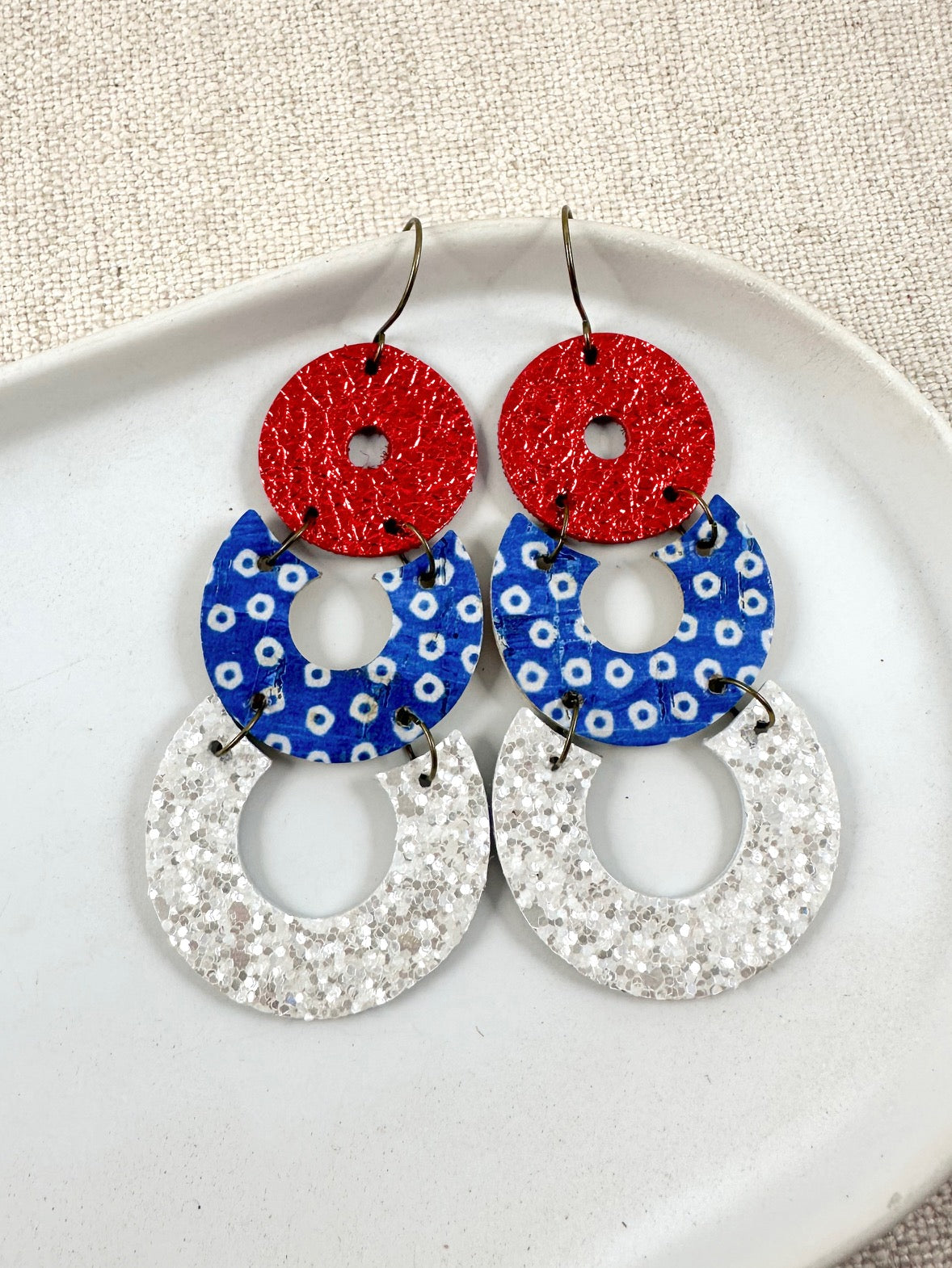 Handmade Firecracker Pop Earrings featuring red sparkle cork, blue dotted cork, and white shimmer genuine leather details.