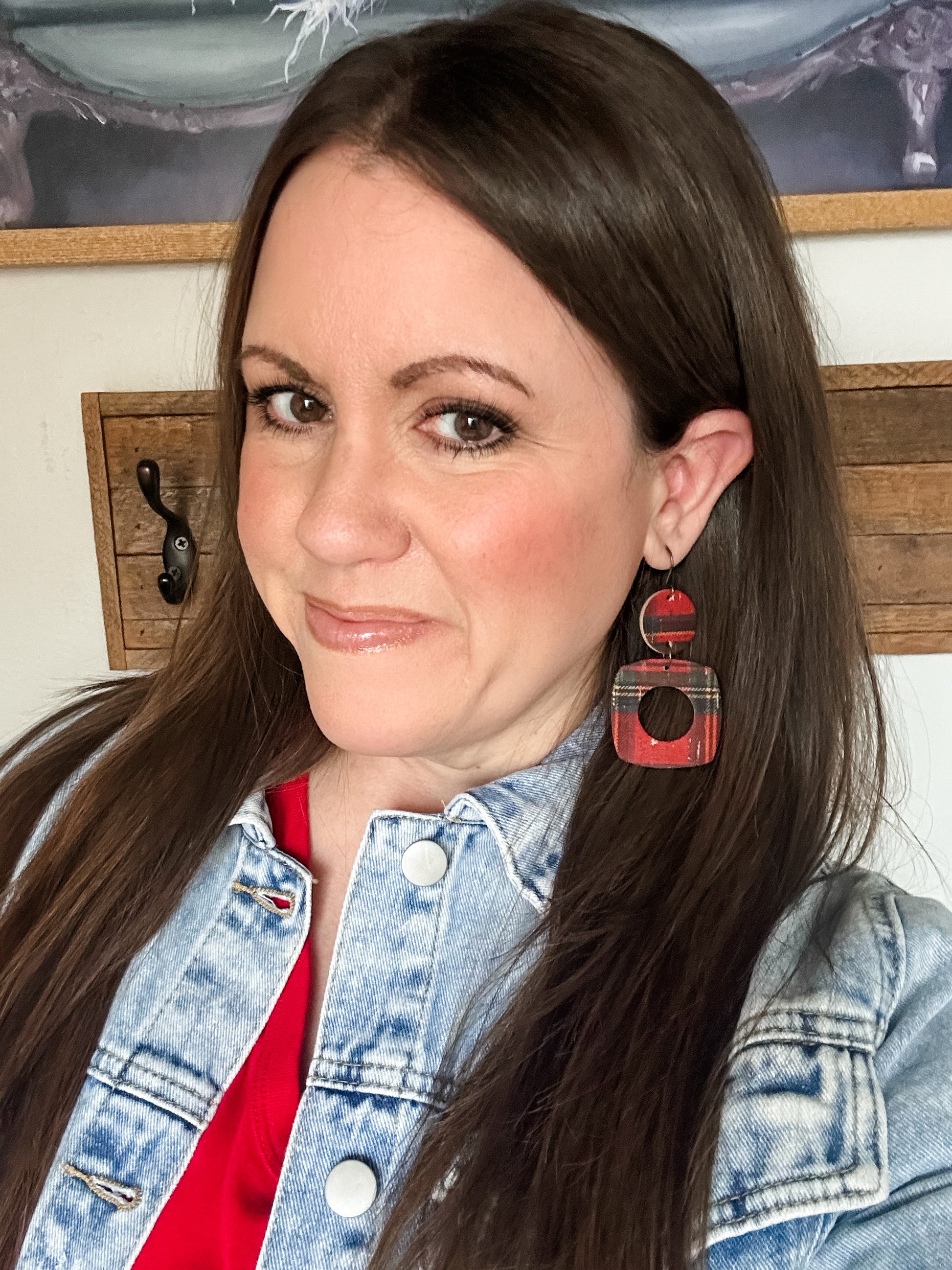 Woman wearing red tartan plaid cork earrings with a geometric cutout, styled with a denim jacket.