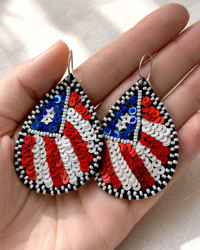 Hand holding Flag of Freedom earrings to show the true 2.25-inch size and lightweight sequin beadwork design.