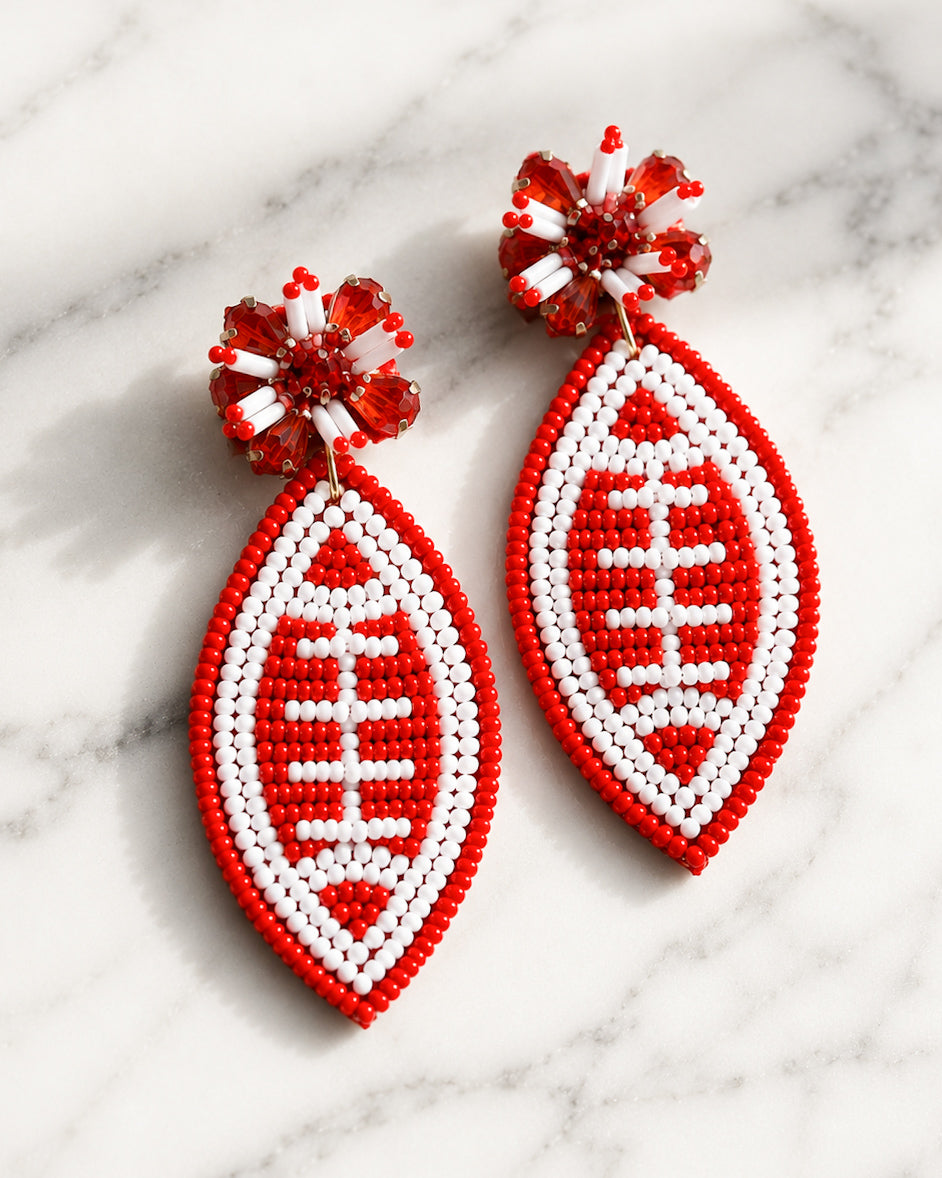 Football & Fireworks red beaded football earrings with crystal accents on white marble