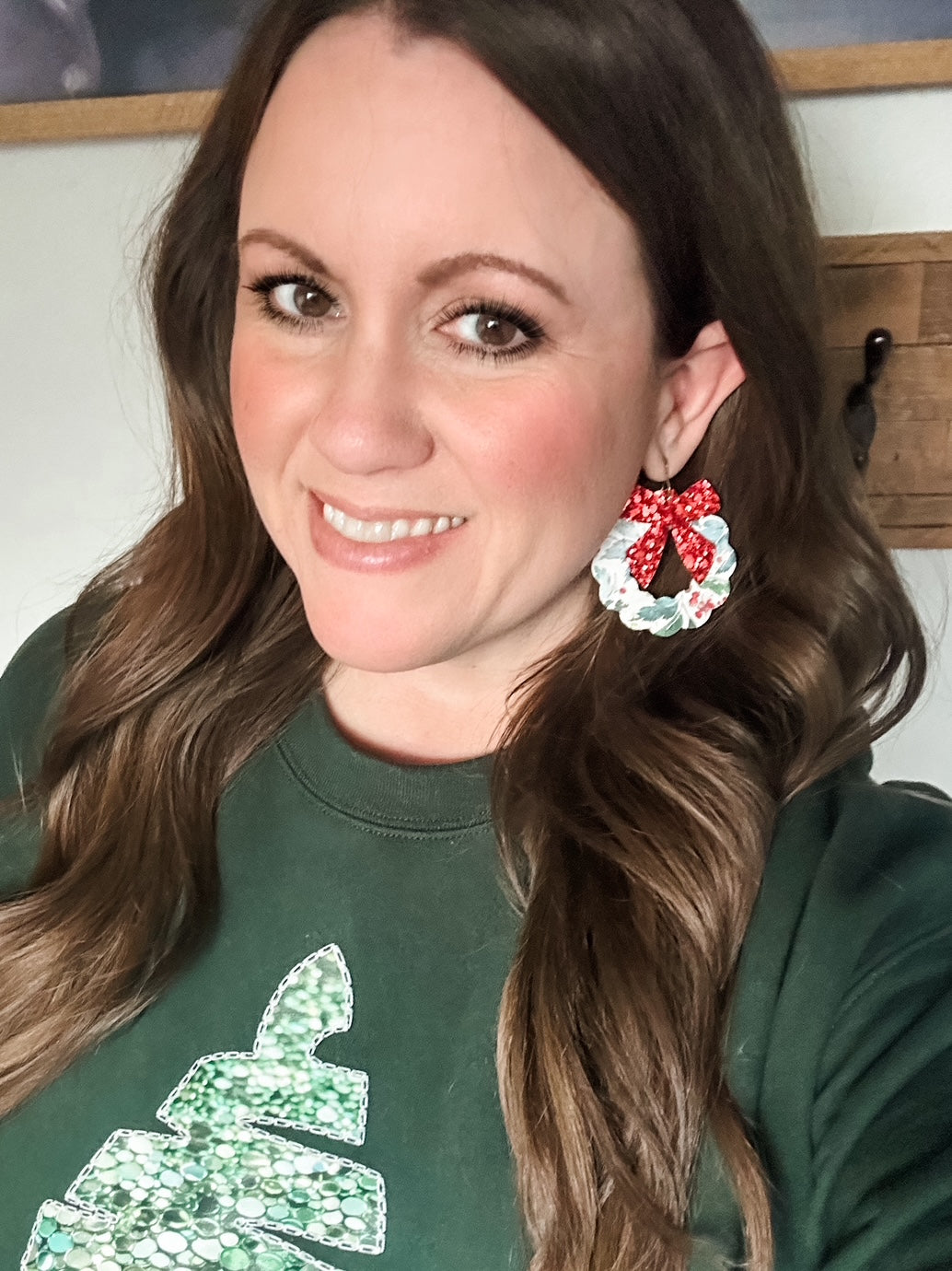 Woman wearing Frosted Berry Wreath Earrings with a red glitter bow and floral cork wreath.