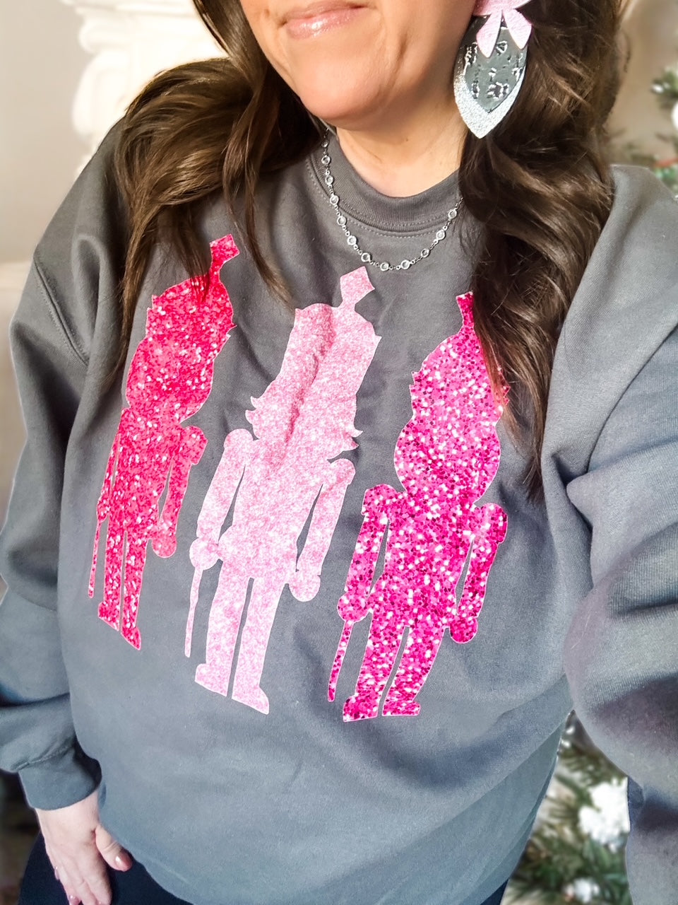 Charcoal Gildan sweatshirt with three pink faux-sequin nutcrackers across the front, cozy holiday crewneck from Anabelle+Oak