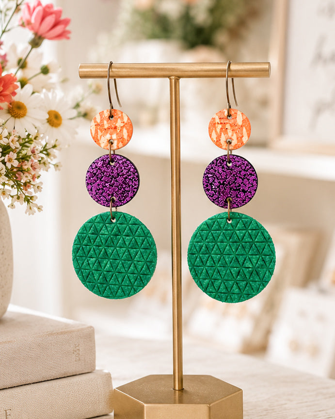 Handmade Garden Party leather and cork earrings displayed on a gold jewelry stand in a bright boutique-inspired setting.