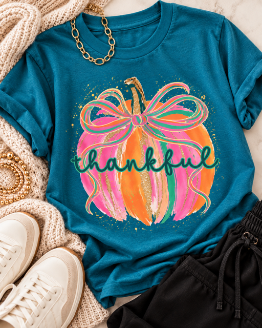 Teal blue Gilded & Thankful fall graphic tee styled with a cream knit cardigan, black pants, neutral sneakers, and gold accessories.