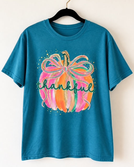 Gilded & Thankful graphic tee in teal blue featuring a colorful pink and orange pumpkin with an oversized bow, gold accents, and thankful lettering.